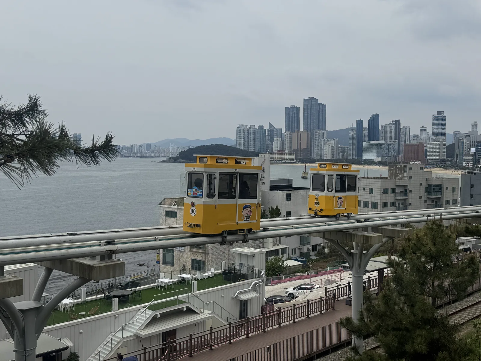 Cabines coloridas do Sky Capsule junto à paisagem costeira de Haeundae