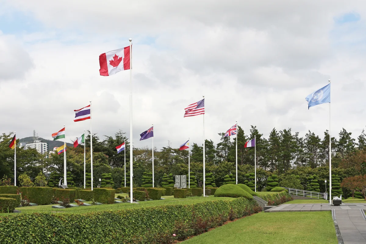 Jardins e bandeiras de países participantes da Guerra da Coreia no Cemitério Memorial da ONU.