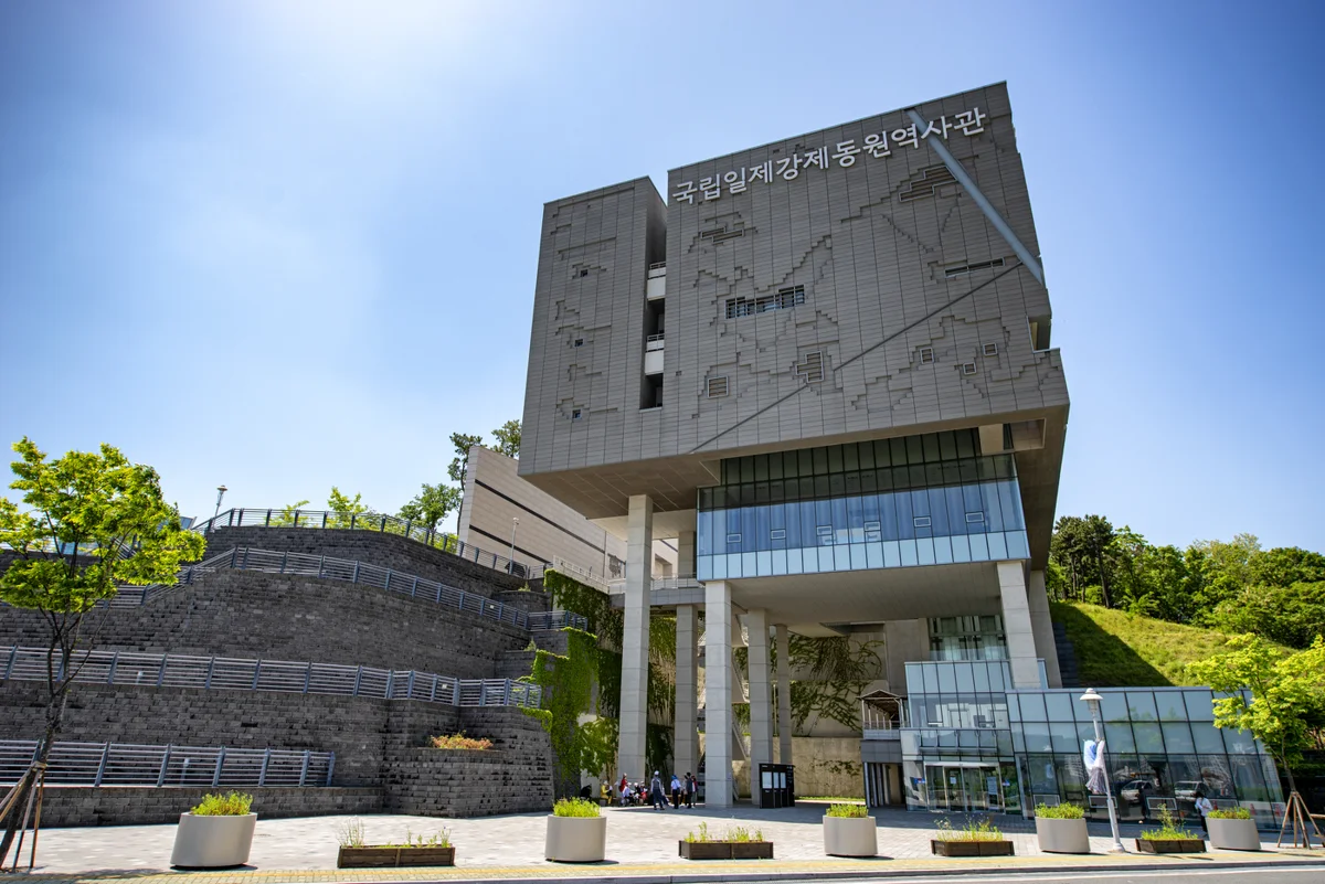Exterior do Museu Nacional da Mobilização Forçada, com nome em coreano na fachada e escadaria lateral.